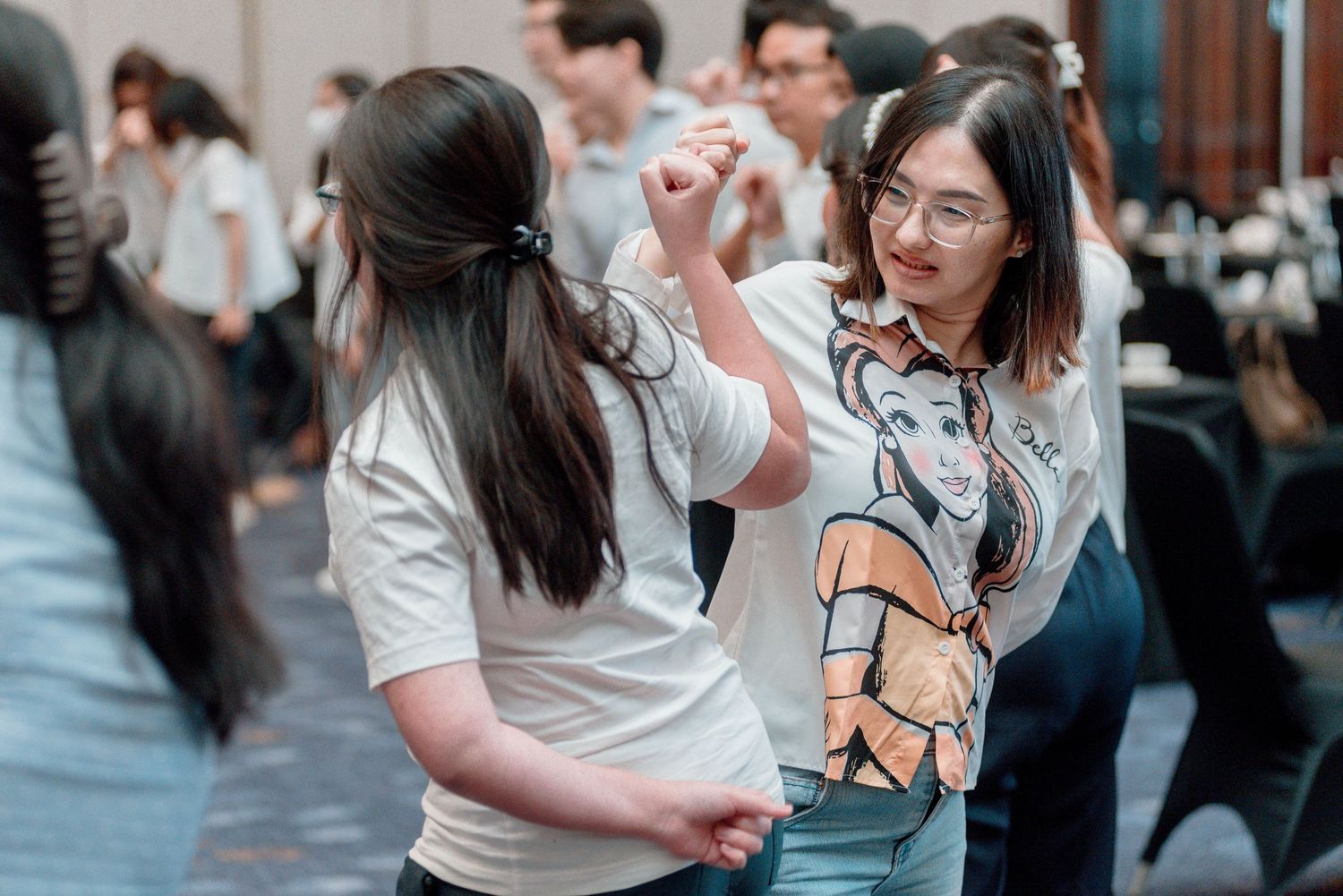 A group of people engaged in conversation at a social gathering, with some wearing casual attire and glasses.