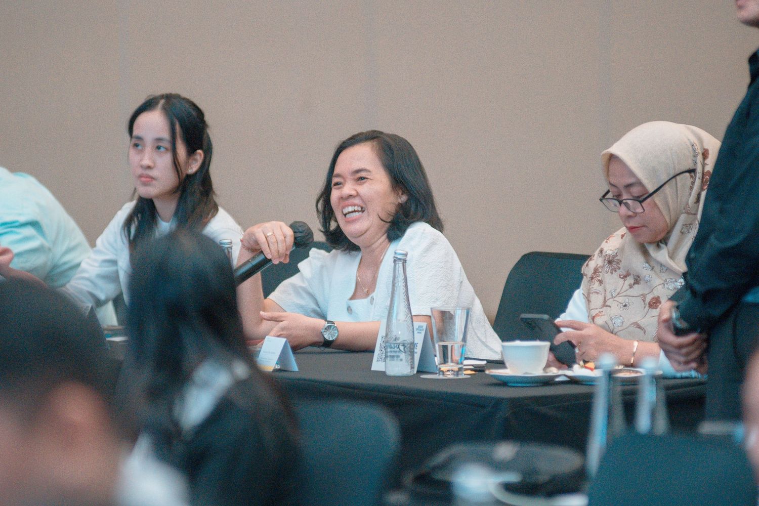 People sit at a conference table during a meeting with beverages and refreshments.
