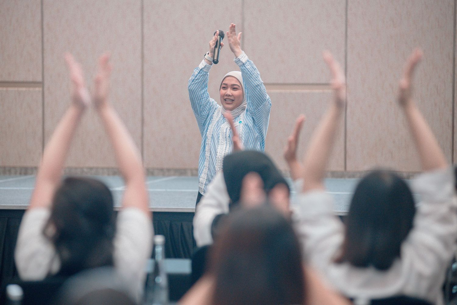 A group of people raising their hands in unison during a seminar or workshop session.
