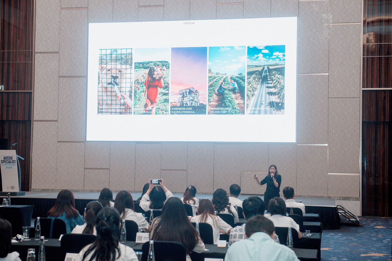 People seated in a conference room with a presentation displayed on a projector screen at the front.