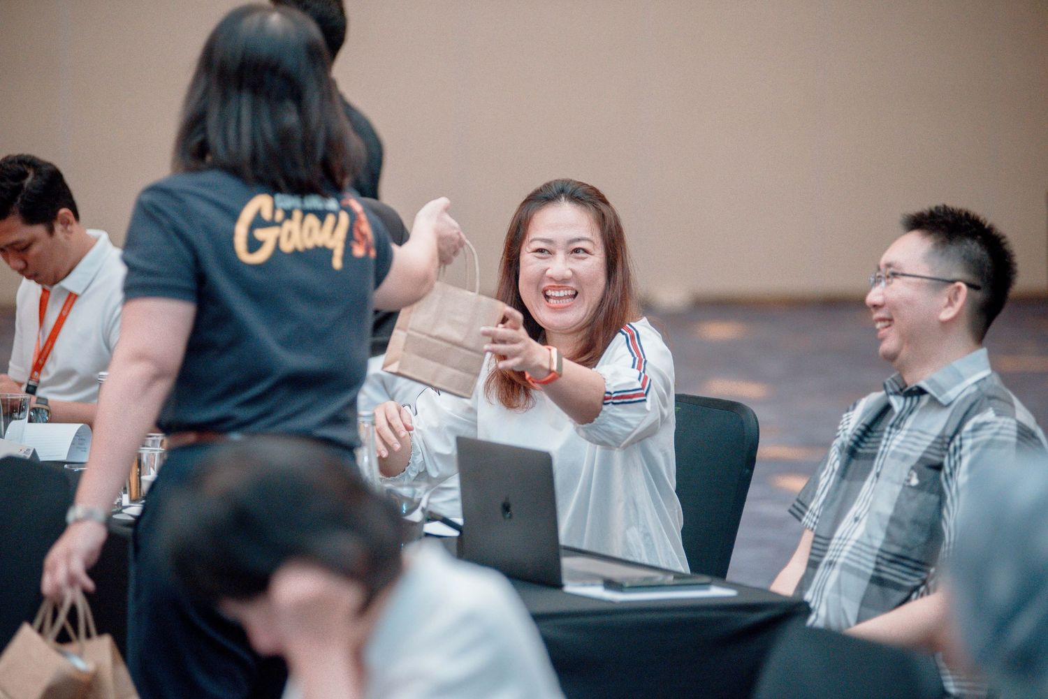 A group of people laughing and interacting during a casual meeting with a laptop on the table.