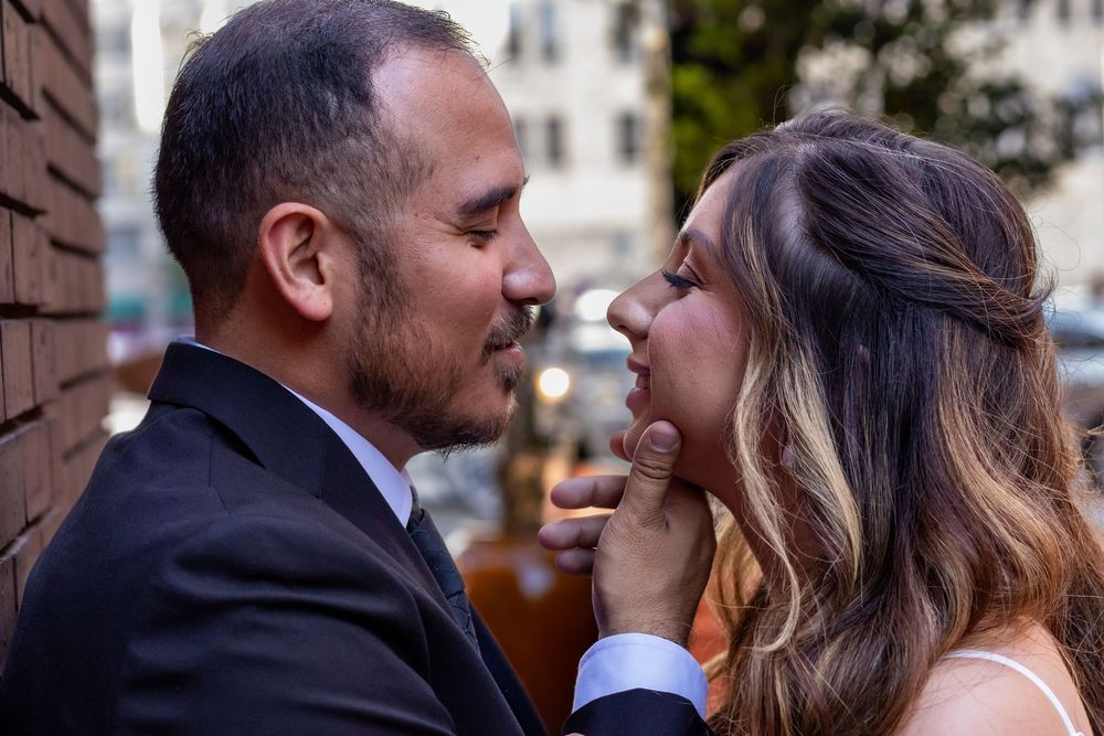 A tender romantic moment between a couple in formal attire sharing an intimate close-up outdoors.