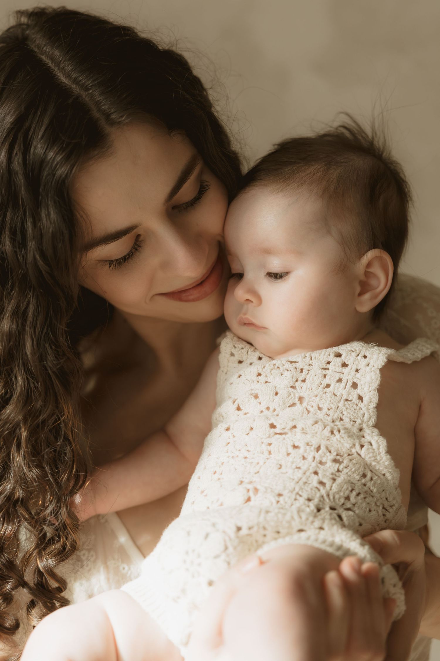 A tender moment captured in sepia tones shows a mother and baby in an intimate embrace.