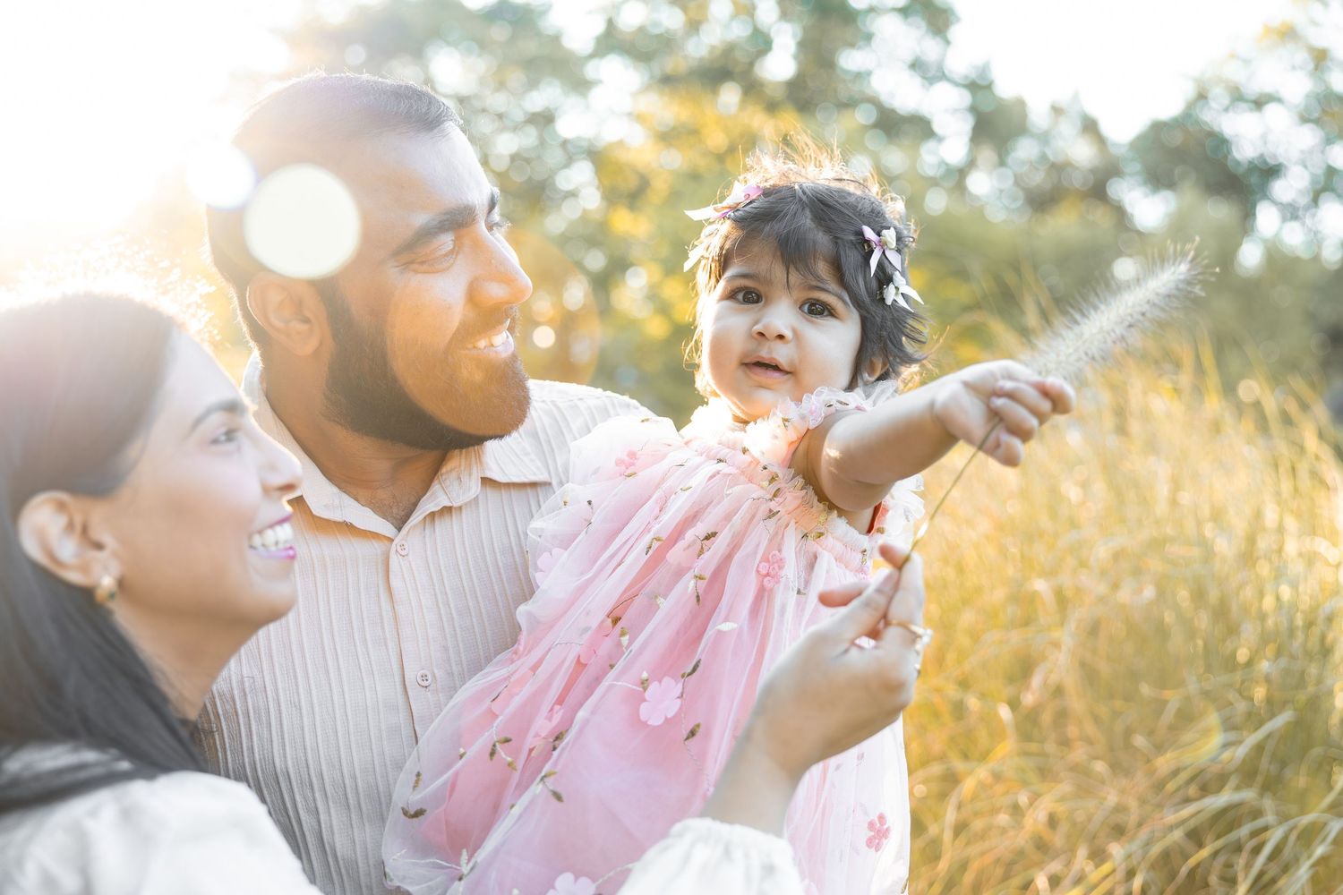 Family enjoying a playful moment together in a sunlit meadow during golden hour.