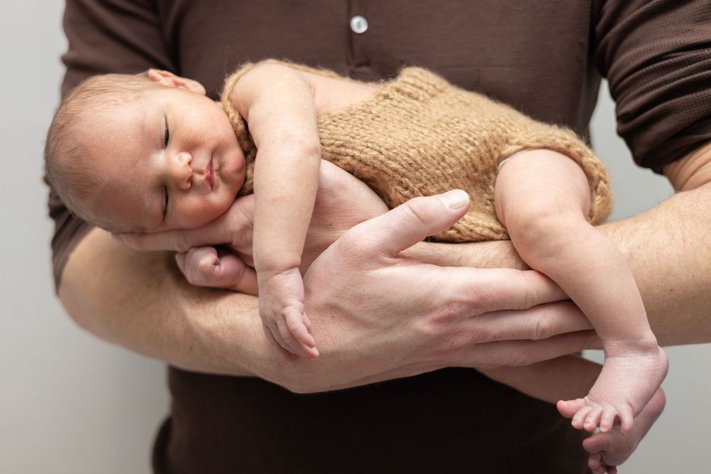 Series of photos showing gentle hands cradling and holding a sleeping newborn in brown and beige tones.