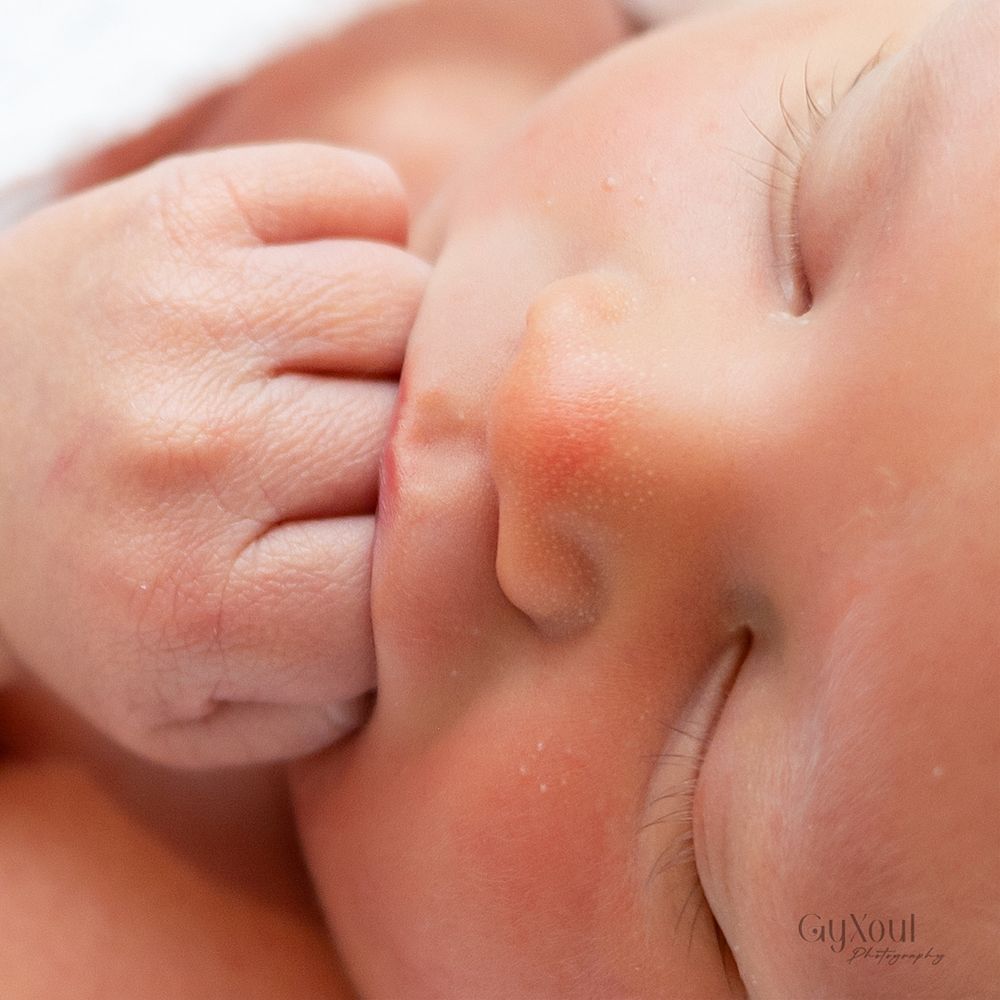 Close-up view of a baby's tiny hand grasping an adult's finger showing tender parent-child connection.
