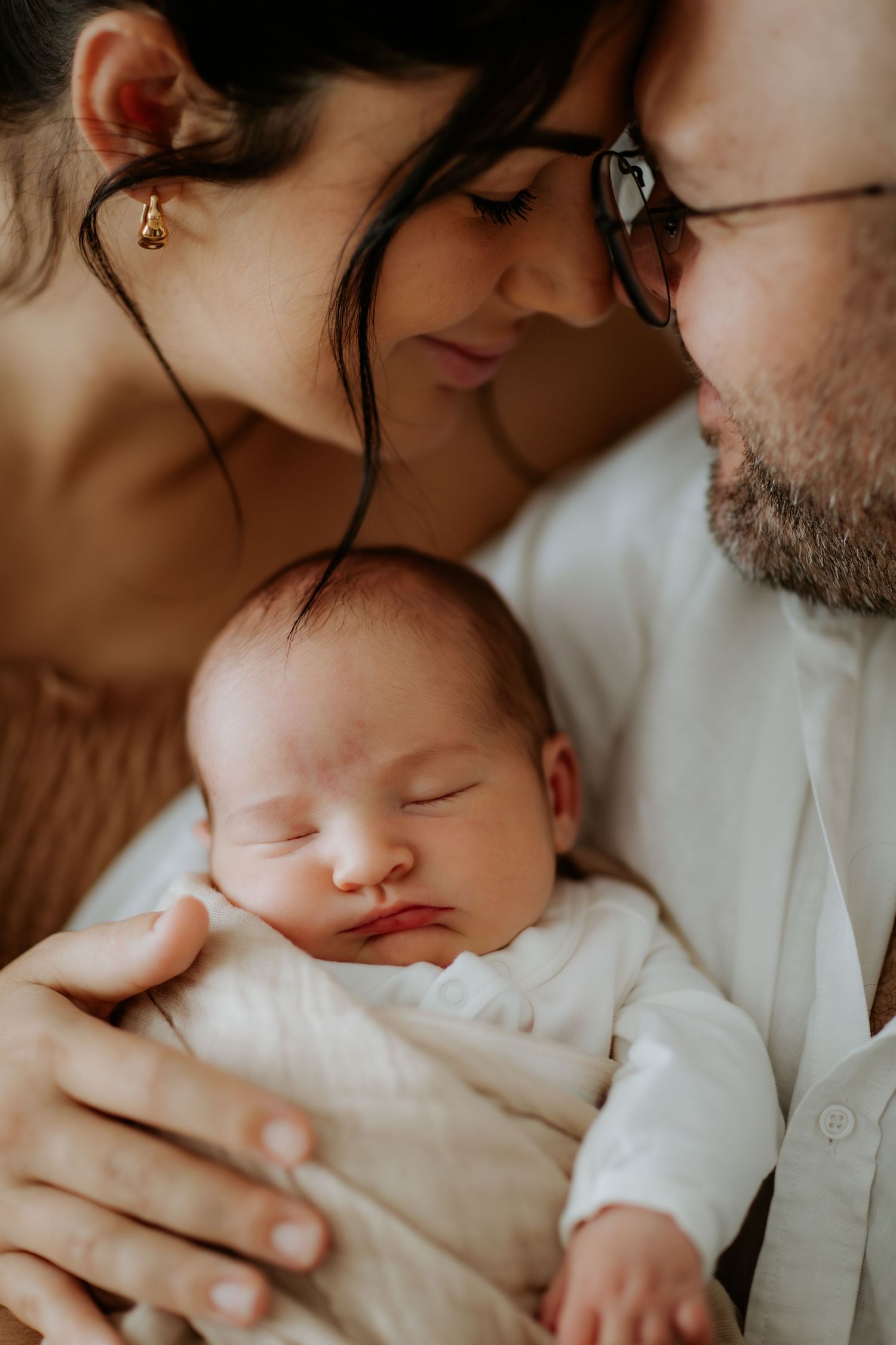 A tender moment between parents and their sleeping newborn baby shown in a series of intimate close-up photographs.
