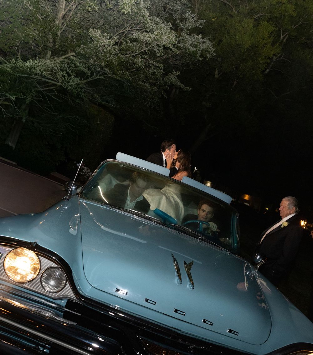 A vintage light blue Ford car illuminated at night during a wedding celebration.