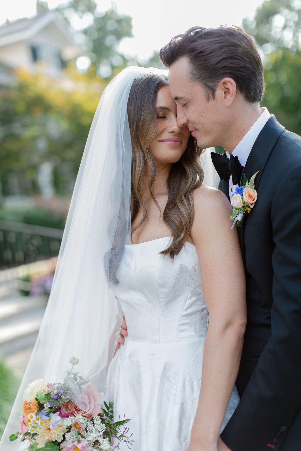 Romantic wedding couple shares intimate moments in an outdoor garden setting with beautiful natural lighting.