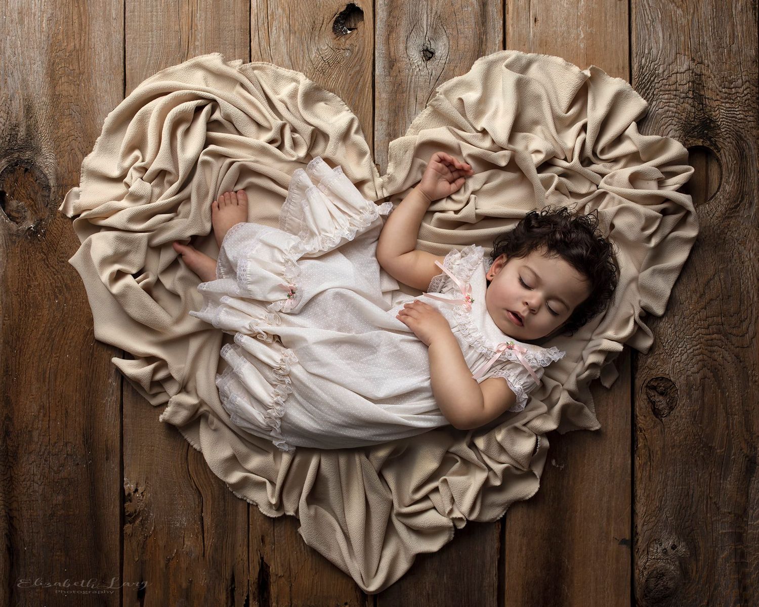 A series of artistic baby portraits showing an infant lying on cream fabric against a rustic wooden backdrop.