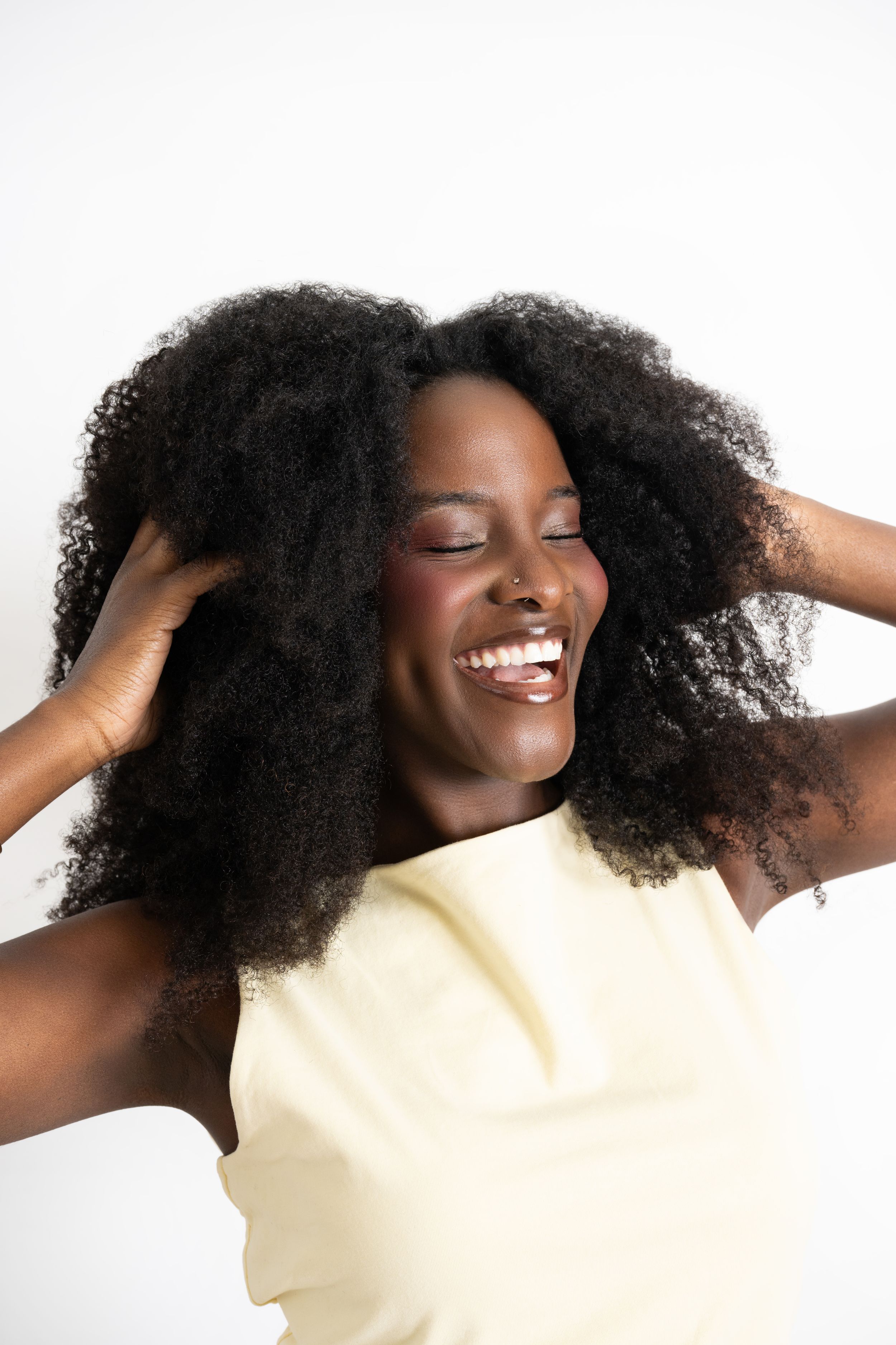 A series of photos showing natural curly hair being styled and fluffed while wearing a cream colored top.