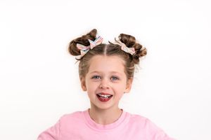 Playful studio portraits with pink clothing and hair accessories against white background.