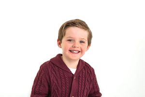 Child in burgundy cable knit sweater shown in various expressions against white background.