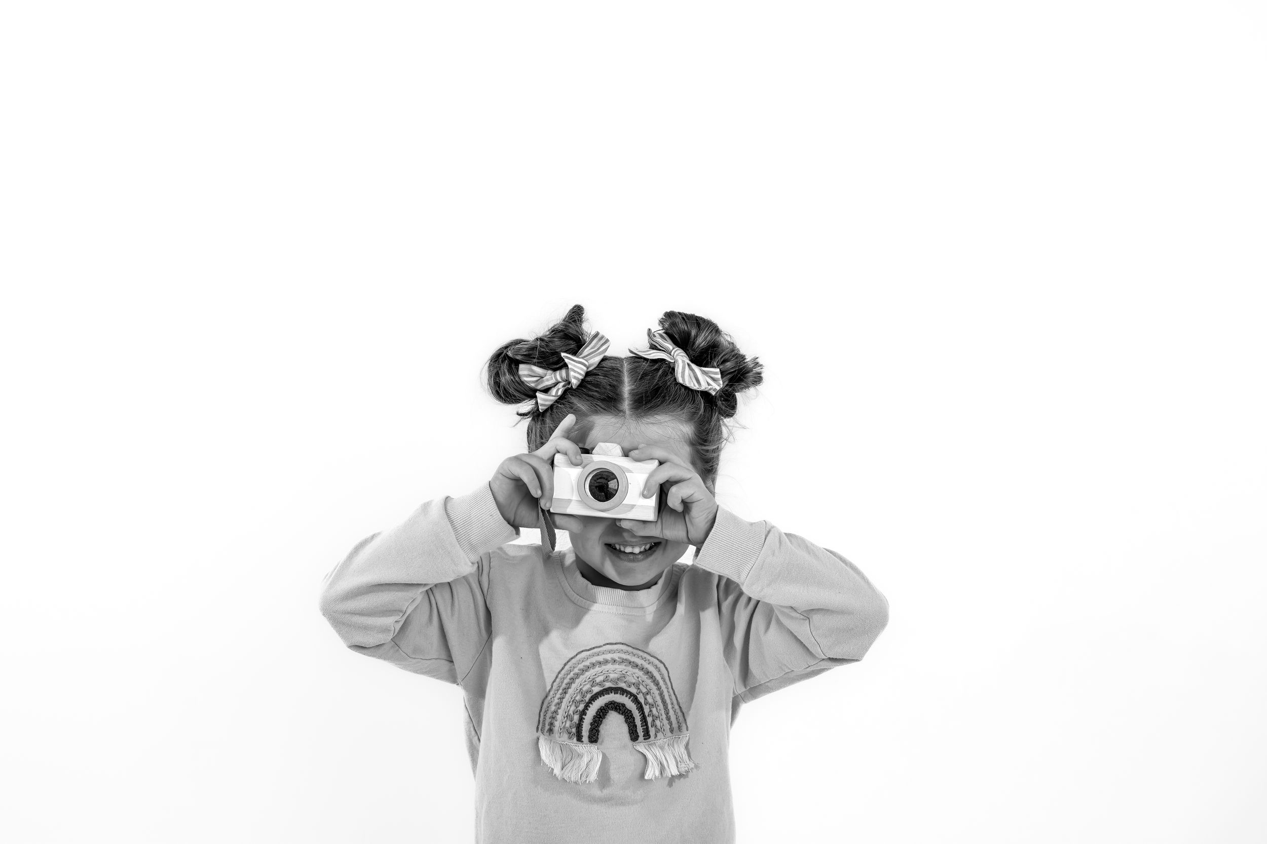 Child making animated faces in a studio setting with a white backdrop for personality portrait minis.