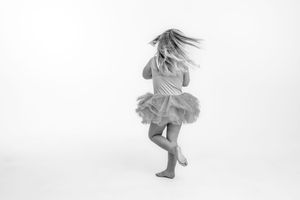Black and white photo of girl in a tutu spinning with hair flying.