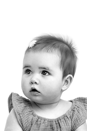 classic image of Close-up black and white portraits of a baby in a ruffled dress looking upward.