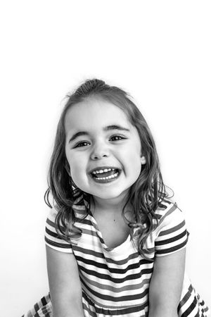 A sequence of four black and white photos shows a child in a striped shirt making playful expressions against a white backdrop.