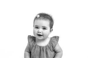 black and white photo of a baby smiling against a white backdrop for personality portraits.