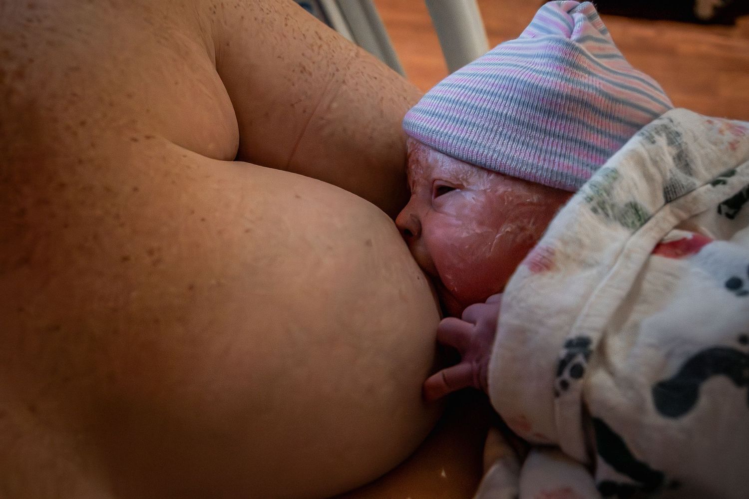A newborn baby nurses from her mother for the first time, just moments after birth in the hospital.