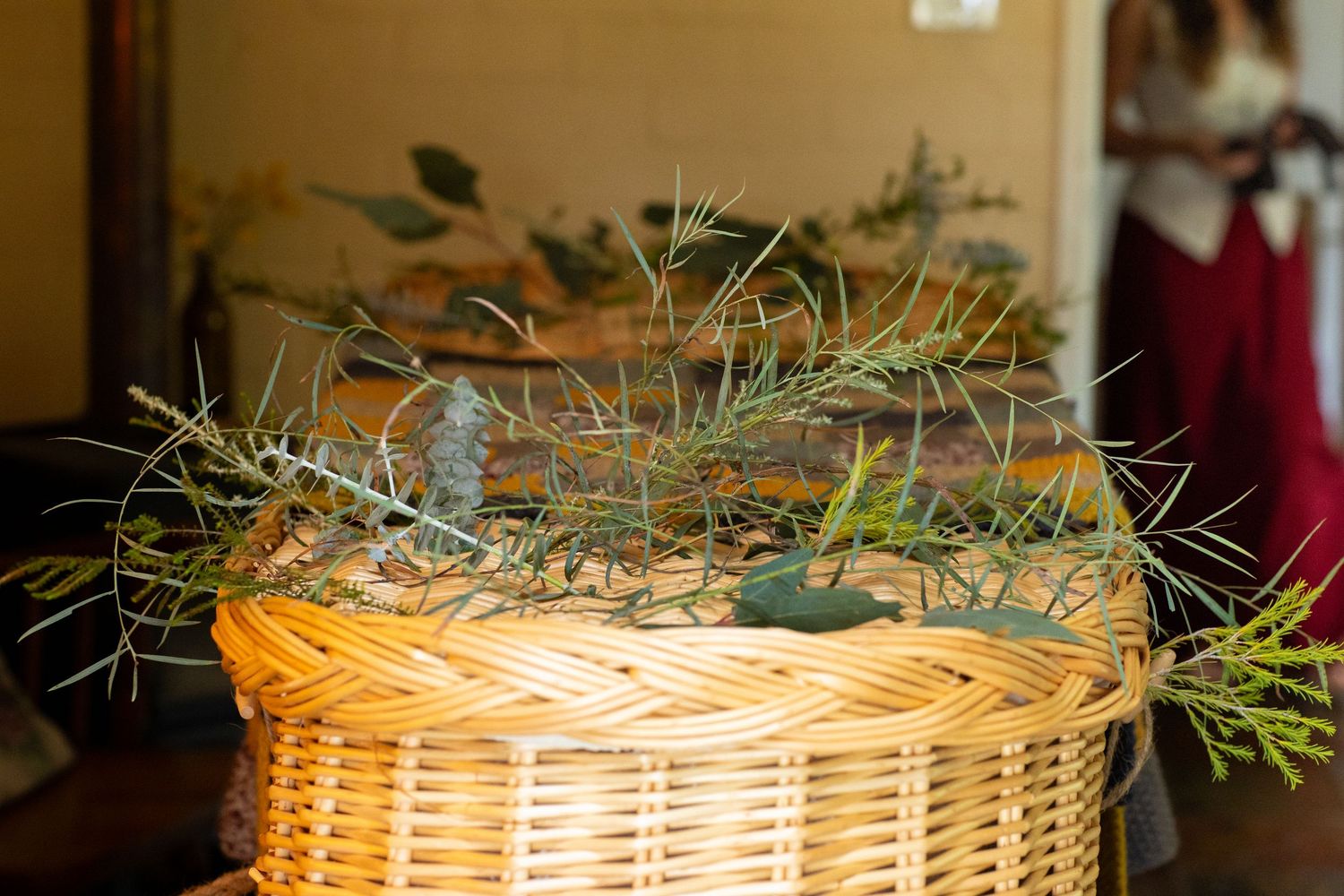 Woven wicker basket with green plants and natural decor displayed in a rustic home setting.