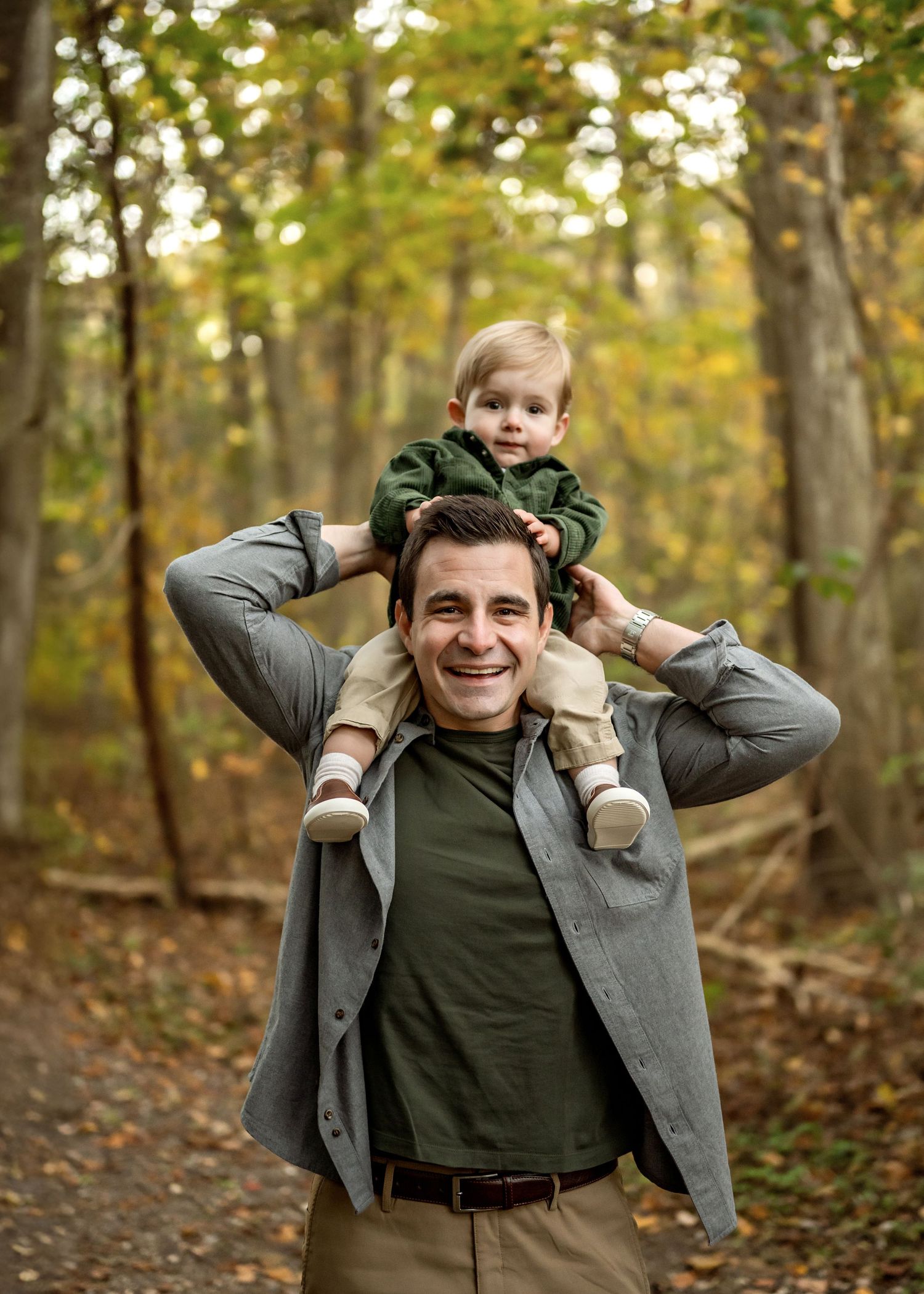 A father and child enjoy quality time together on an autumn trail surrounded by golden fall foliage in the woods.