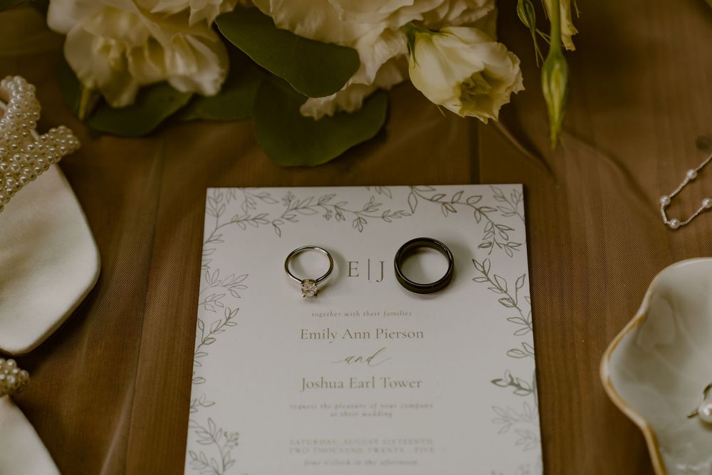 Wedding invitations and details laid out on a rustic wooden surface with elegant calligraphy.