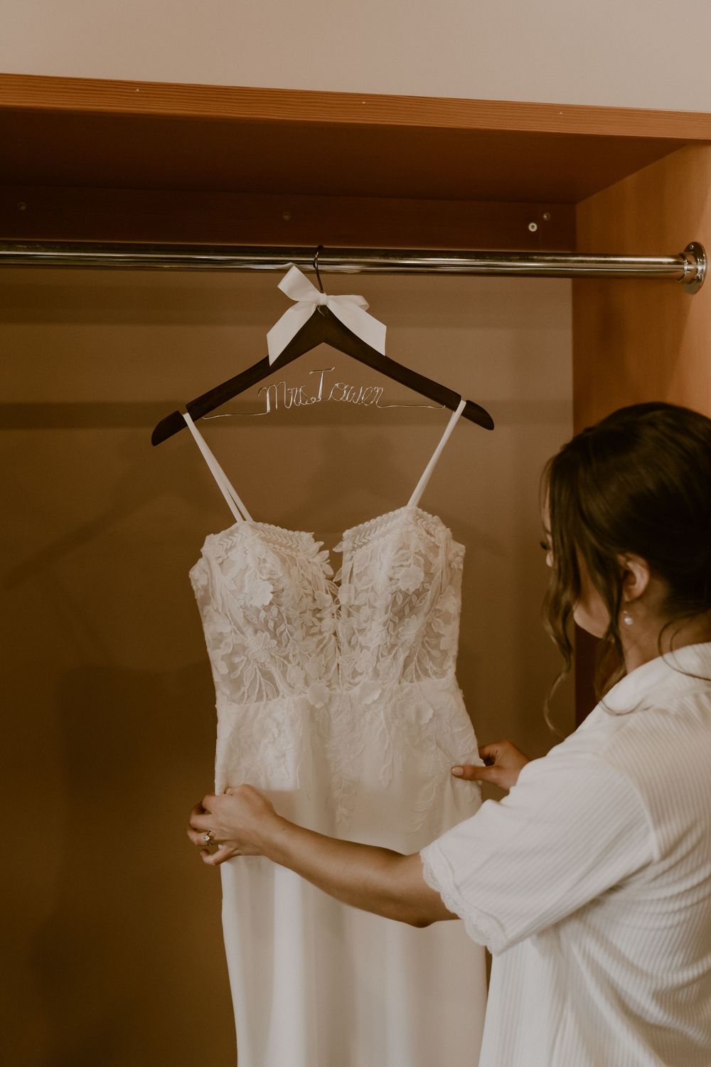 Wedding dress preparation sequence showing white gown being carefully arranged and adjusted on a hanger in closet.