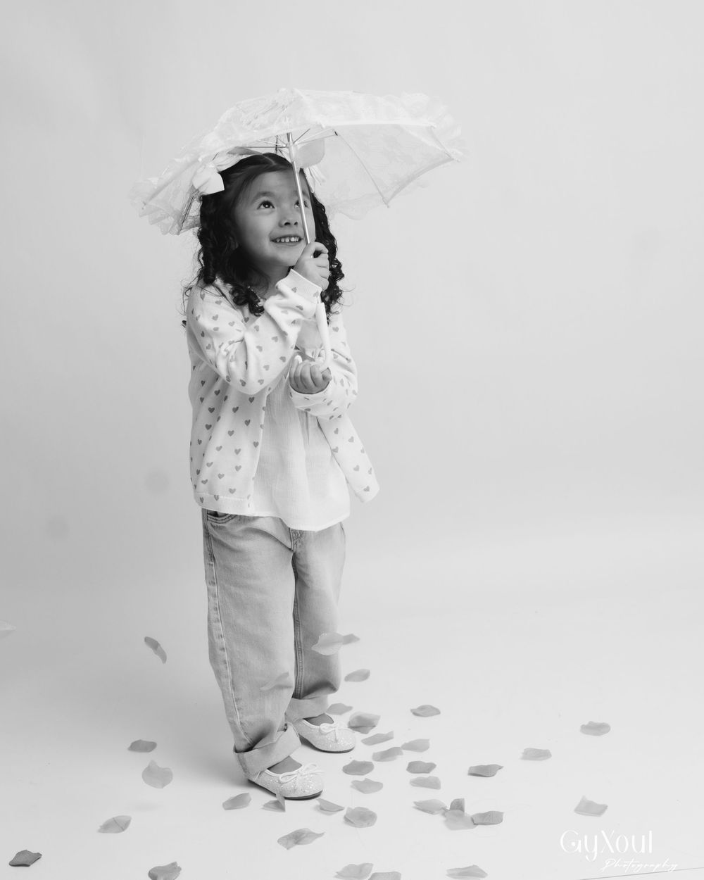 A series of black and white photos showing a toddler in white clothing walking on a floor scattered with leaf shapes.