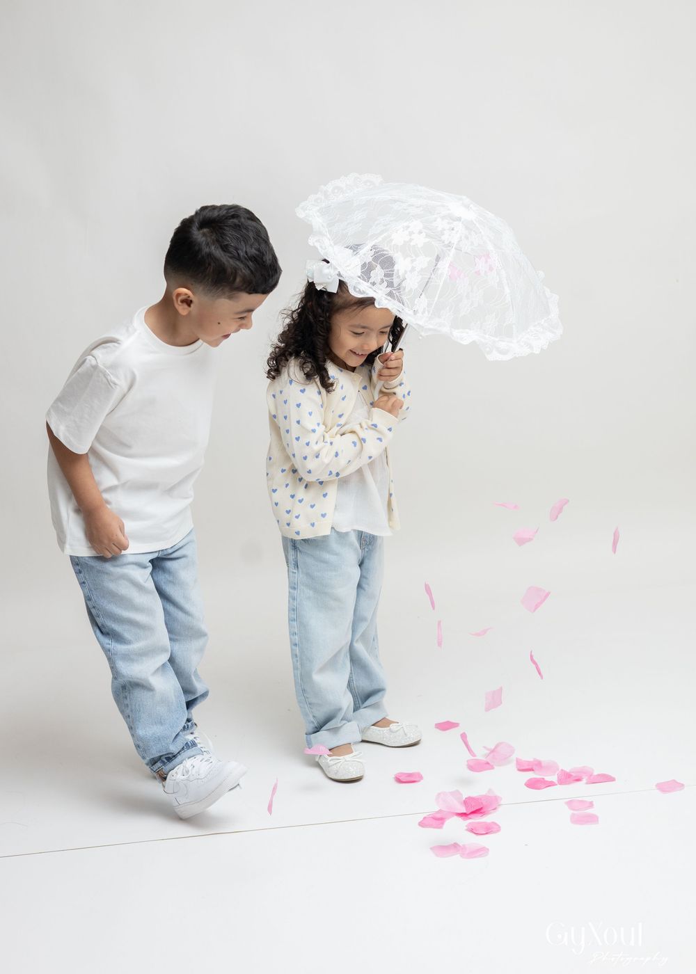 A series of four photos showing someone in jeans and white shirt placing pink paper hearts on a light gray floor.