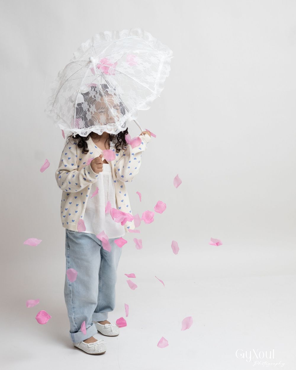 A sequence showing pink rose petals being tossed and falling against a light gray studio backdrop.