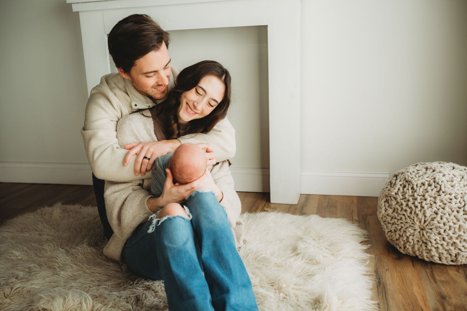 A couple sits together on a plush white rug, sharing an intimate moment in their cozy living room.
