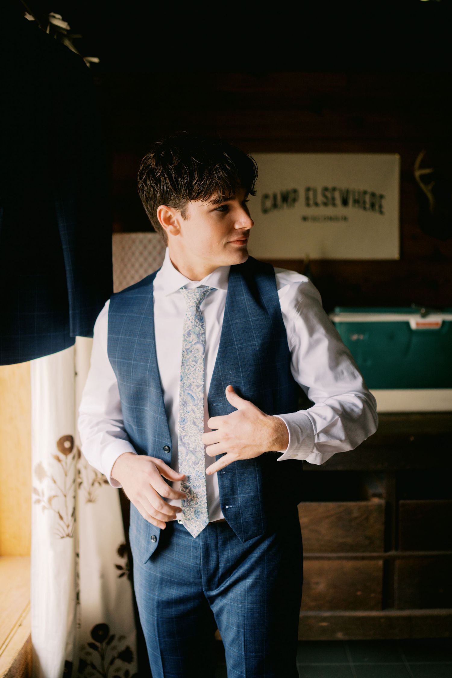 A person in a navy blue vest and white dress shirt adjusts their tie in a series of candid getting-ready photos.