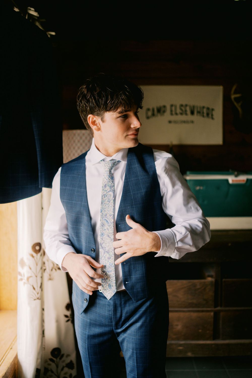 A person in a navy blue vest and white dress shirt adjusts their tie in a series of candid getting-ready photos.