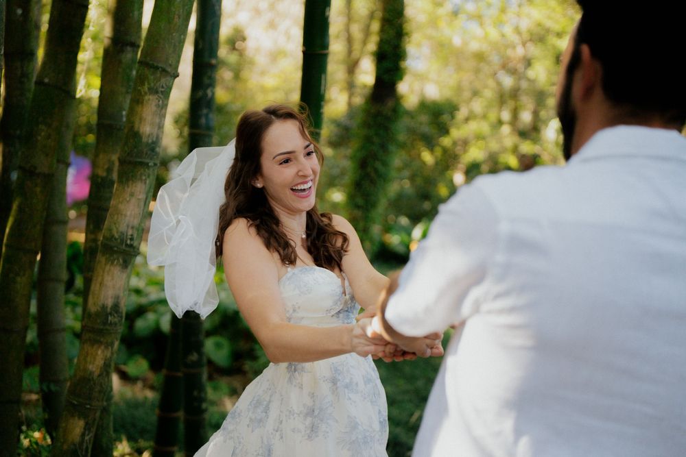 Couple shares a romantic moment in a sunlit garden setting with lush greenery in the background.