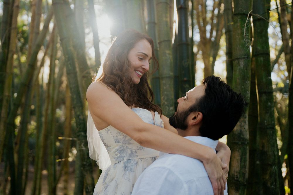 A couple shares a tender moment in a sunlit forest during their wedding photoshoot.