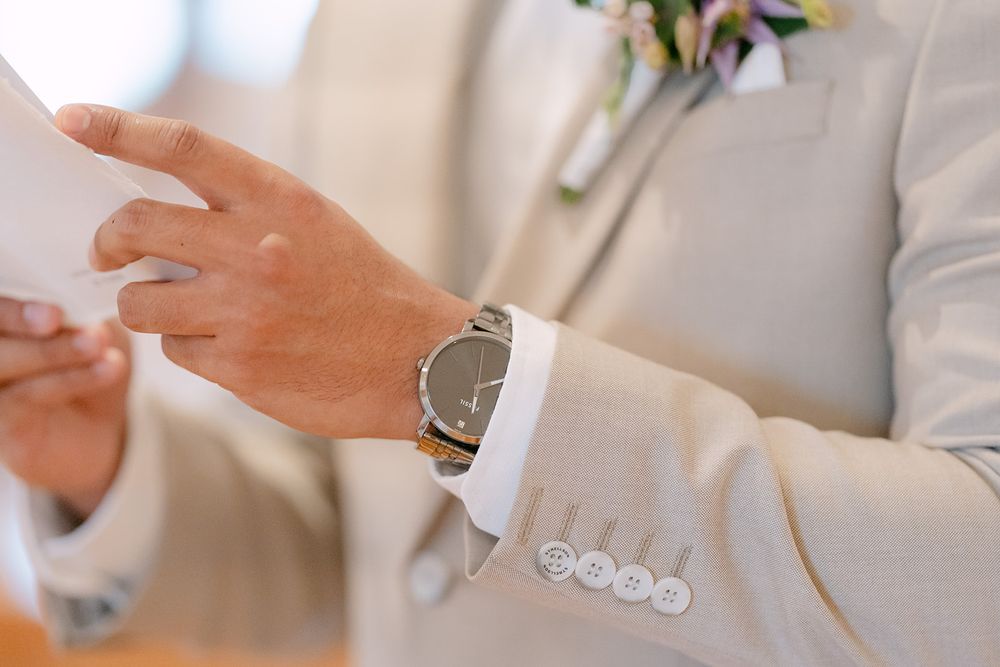 Close-up of hands gesturing during a conversation, with one person wearing a white suit jacket visible.