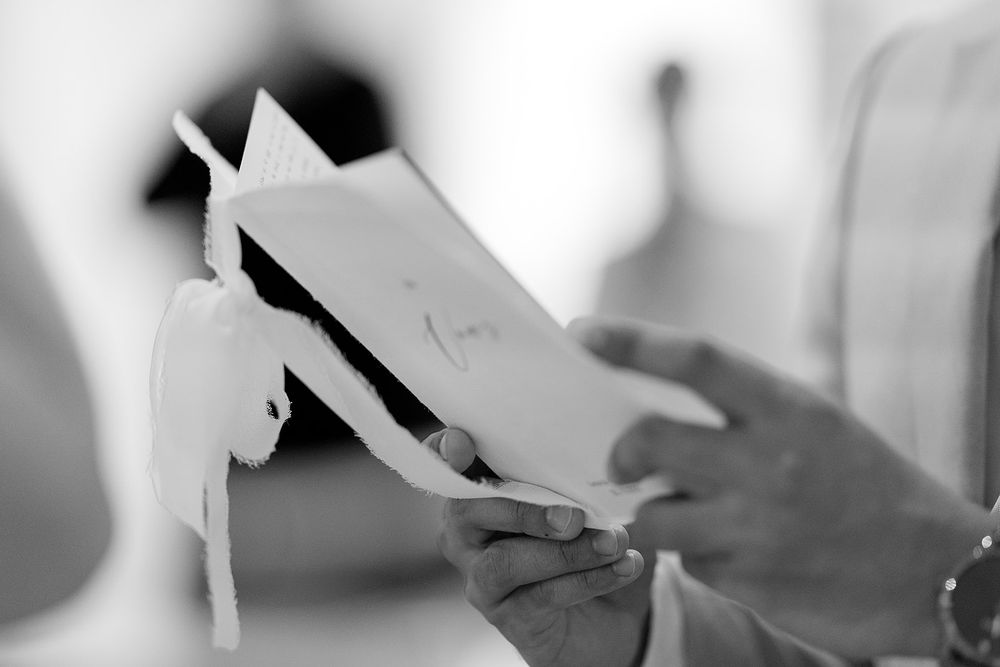 Close-up black and white image of hands holding paper documents against a blurred background.