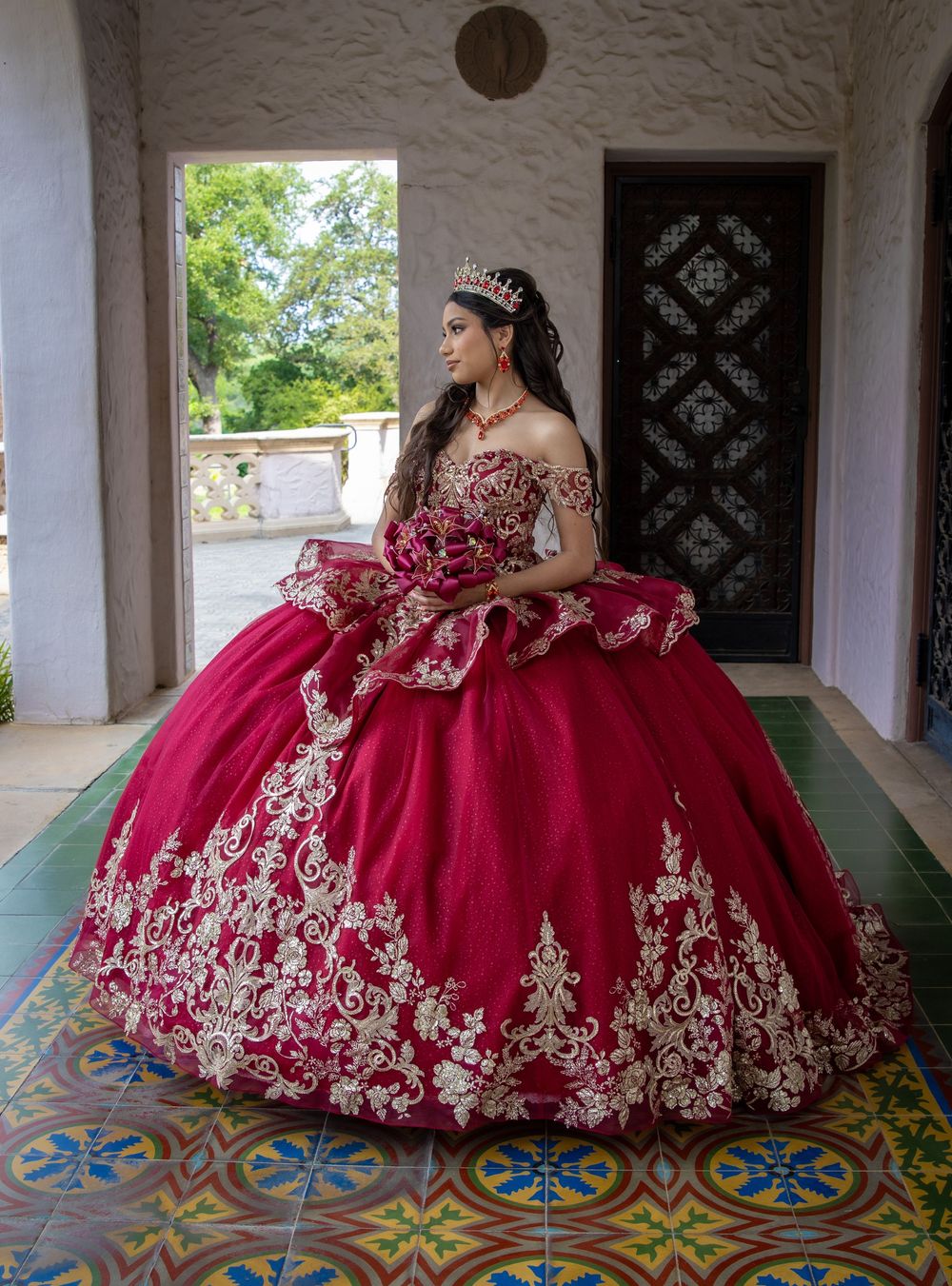 Full-length portrait of a magenta ball gown with white lace appliques on decorative tile flooring.