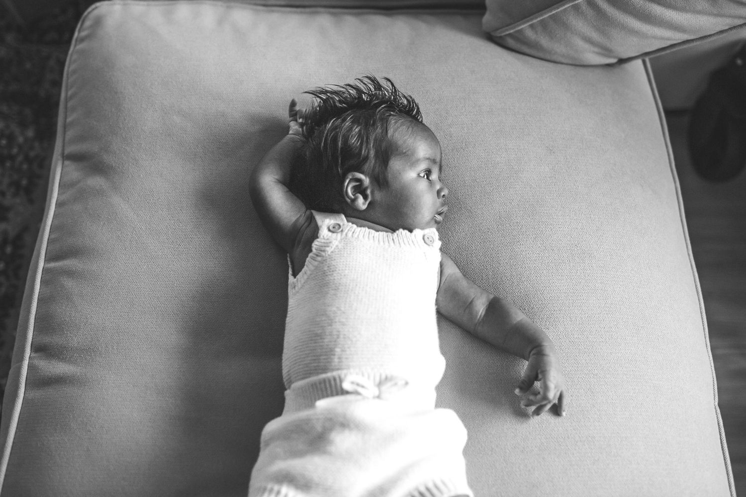 A sleeping newborn baby wearing a white knit romper lies on a light gray blanket in various peaceful positions.