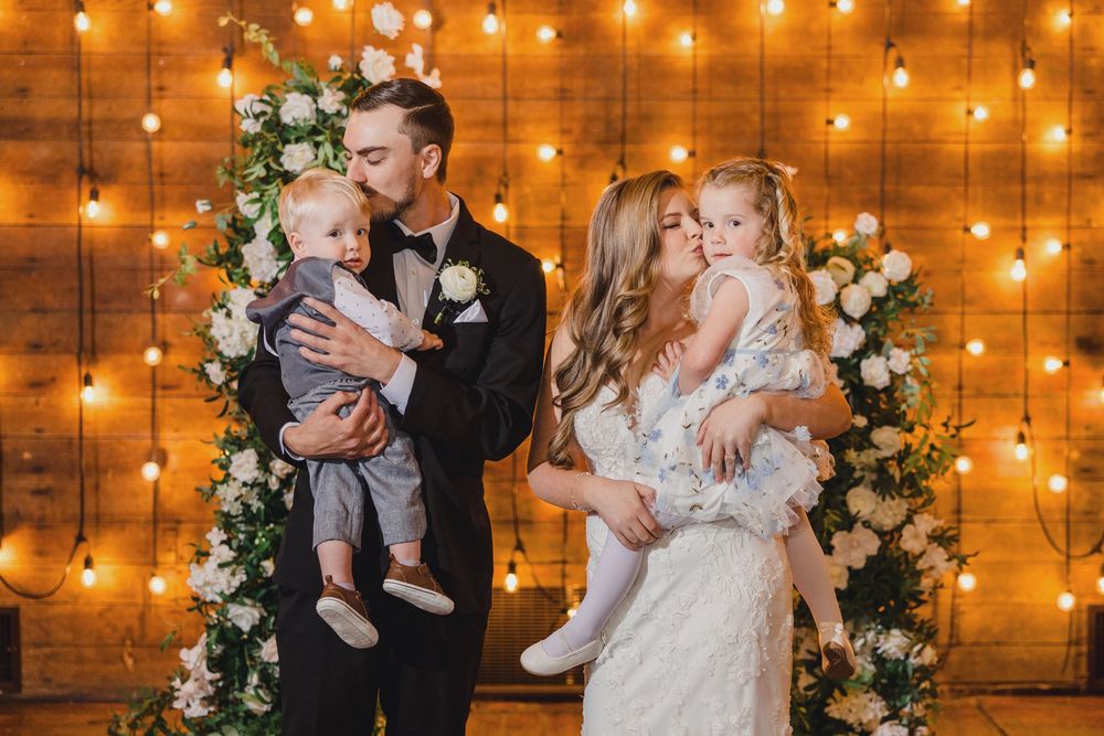 Wedding celebration scene with warm string lights and floral arch decorations creating an intimate atmosphere.
