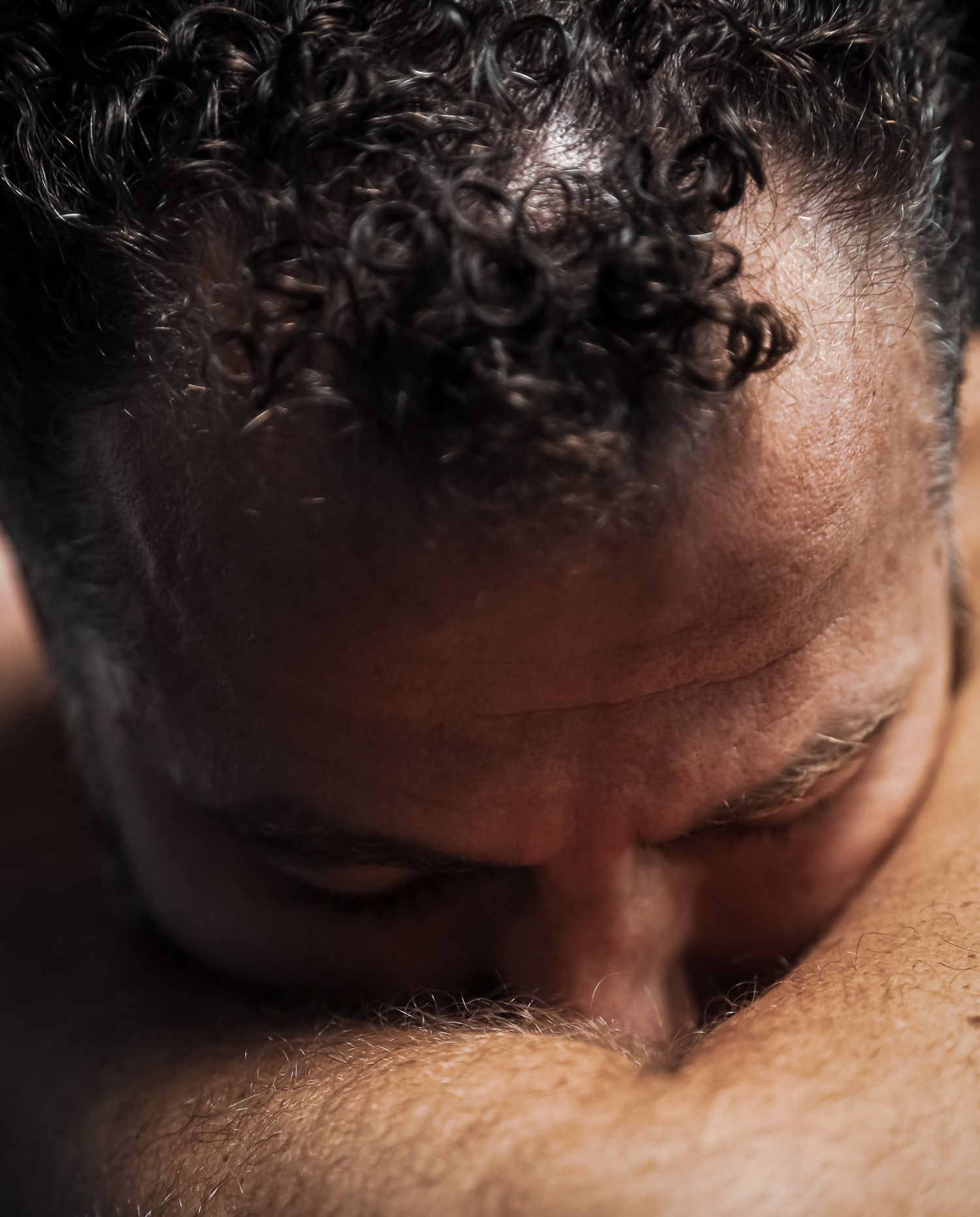 Close-up top-down view of a man with curly hair looking downward.