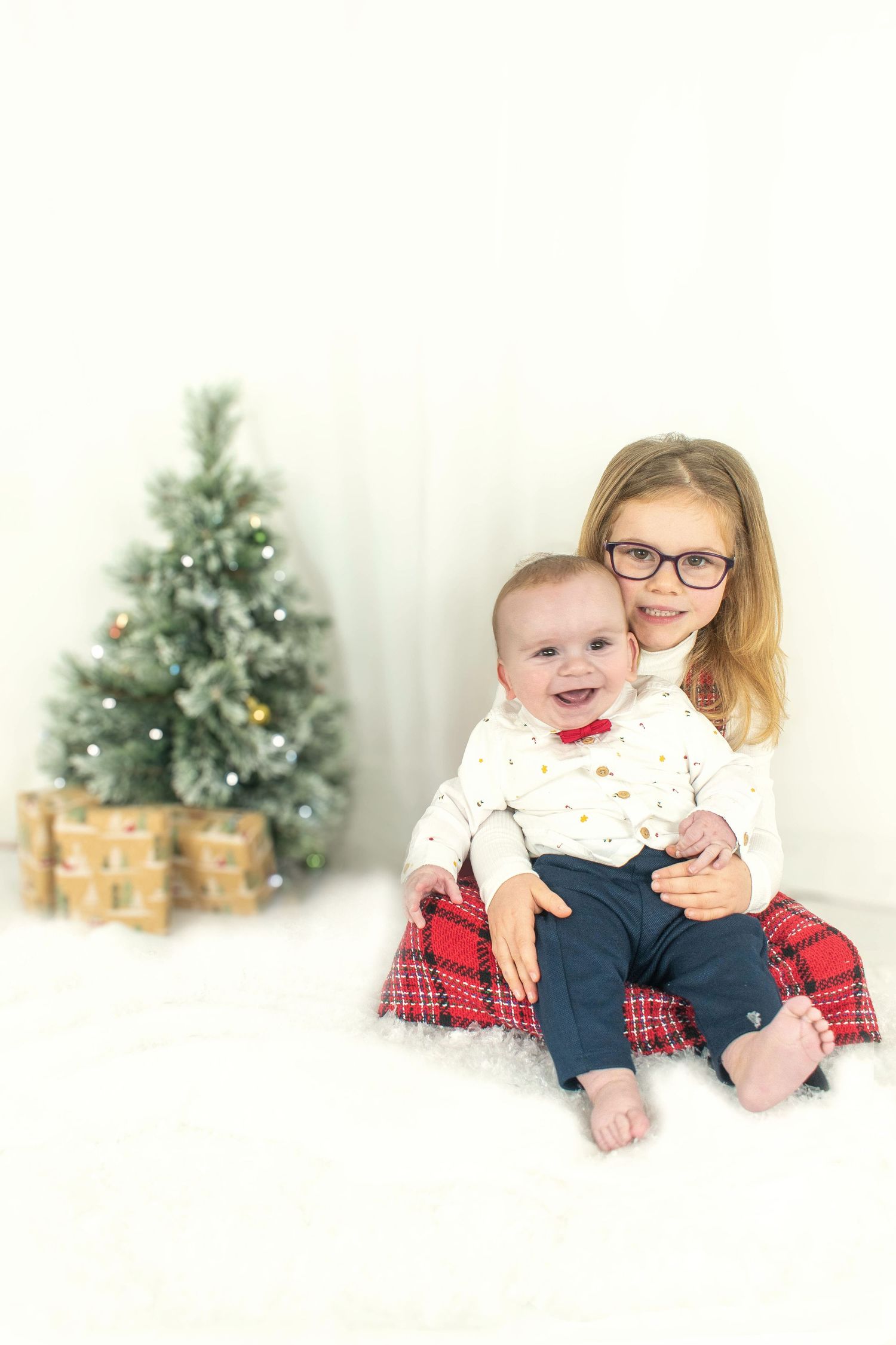 Holiday portrait with Christmas tree and wrapped presents in background.