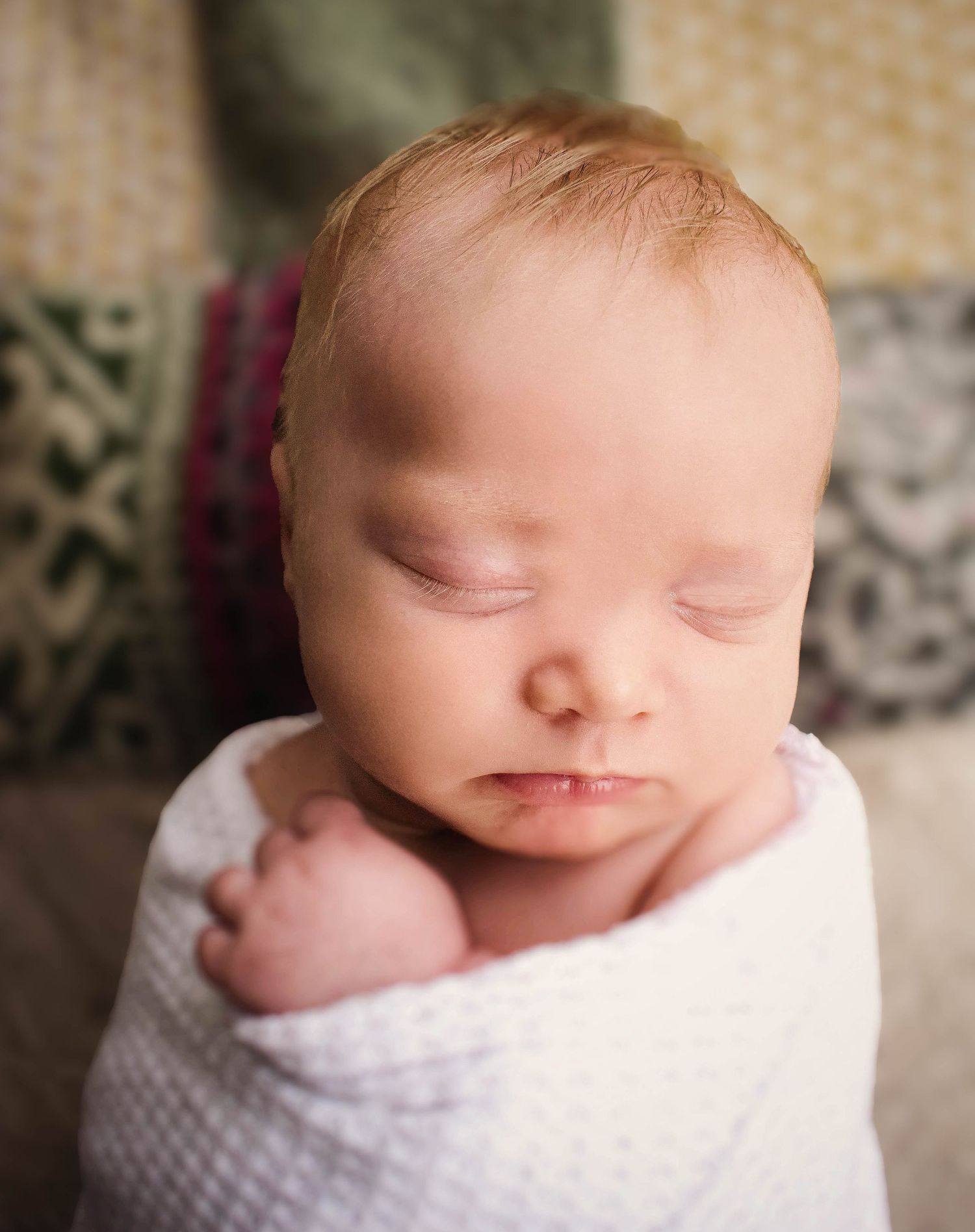 Artistic macro shots of sleeping newborn in soft white wrap.