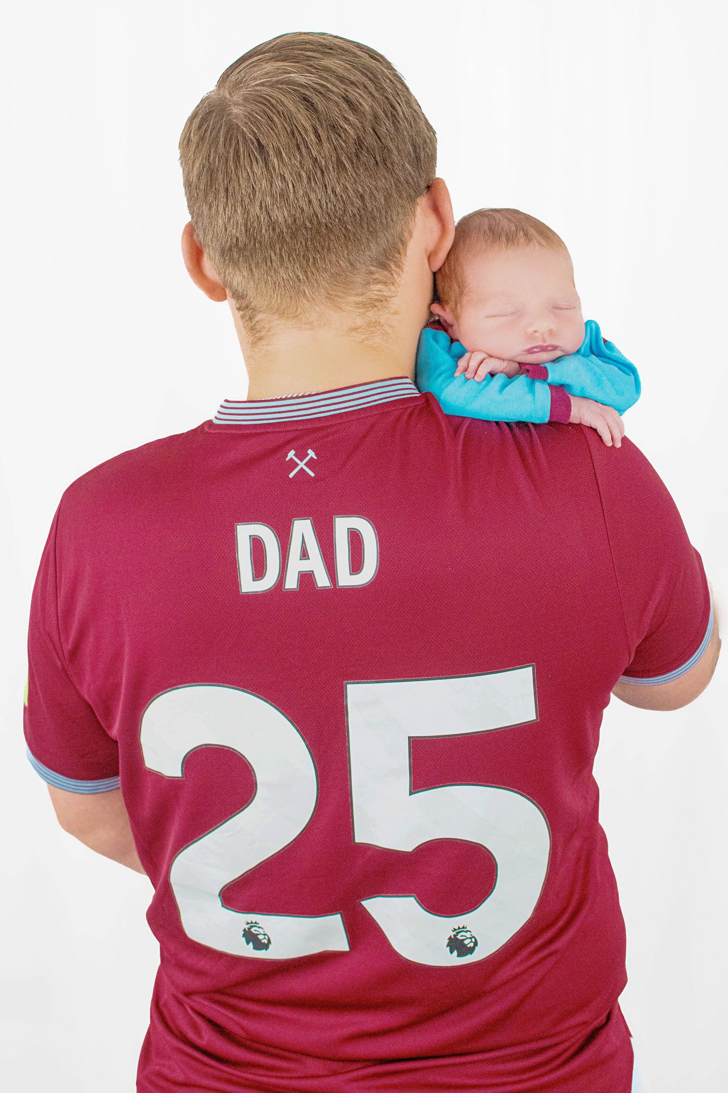 Baby resting on parent wearing burgundy soccer jersey with number 25 and 'DAD' text.