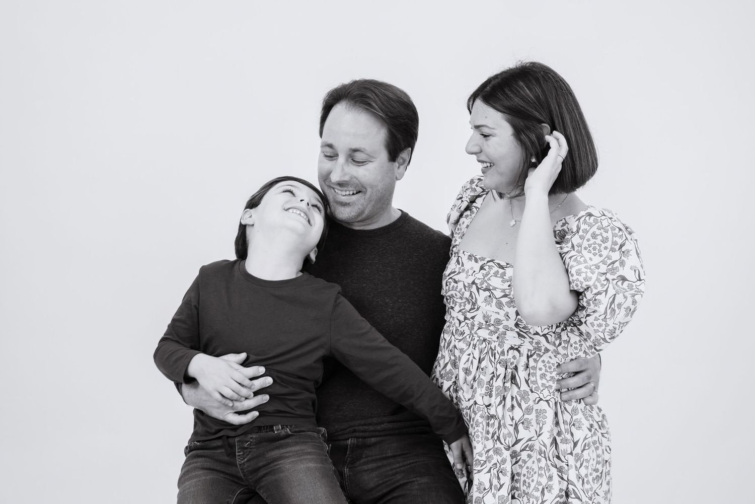 Black and white candid photo of three people sharing a light-hearted moment together.
