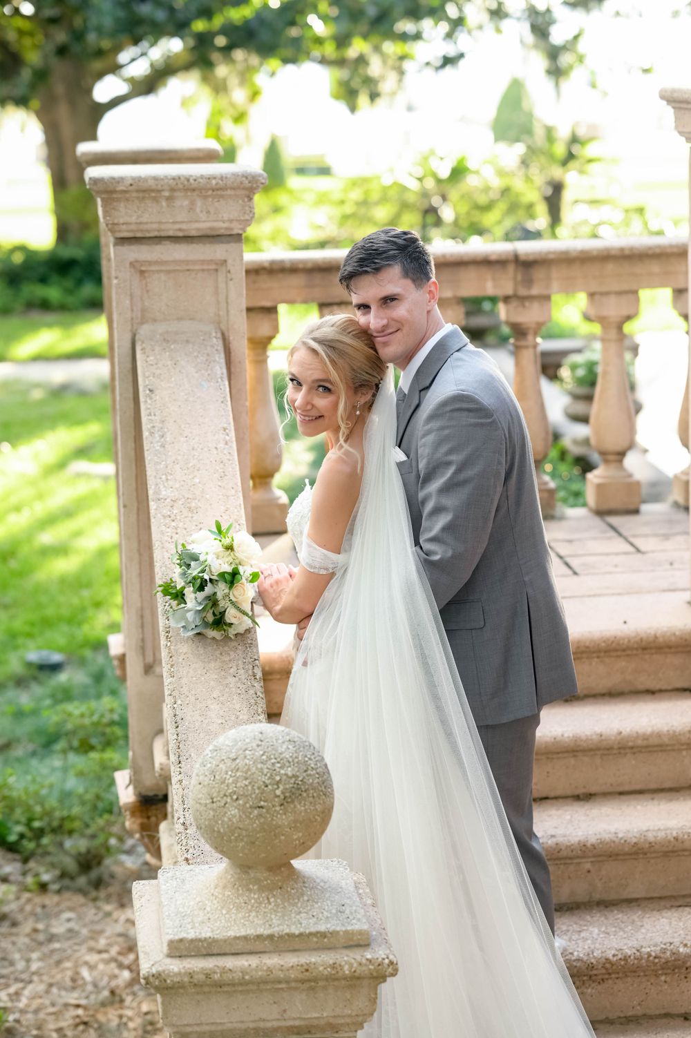 Romantic wedding portrait on ornate stone staircase with classic architectural details.