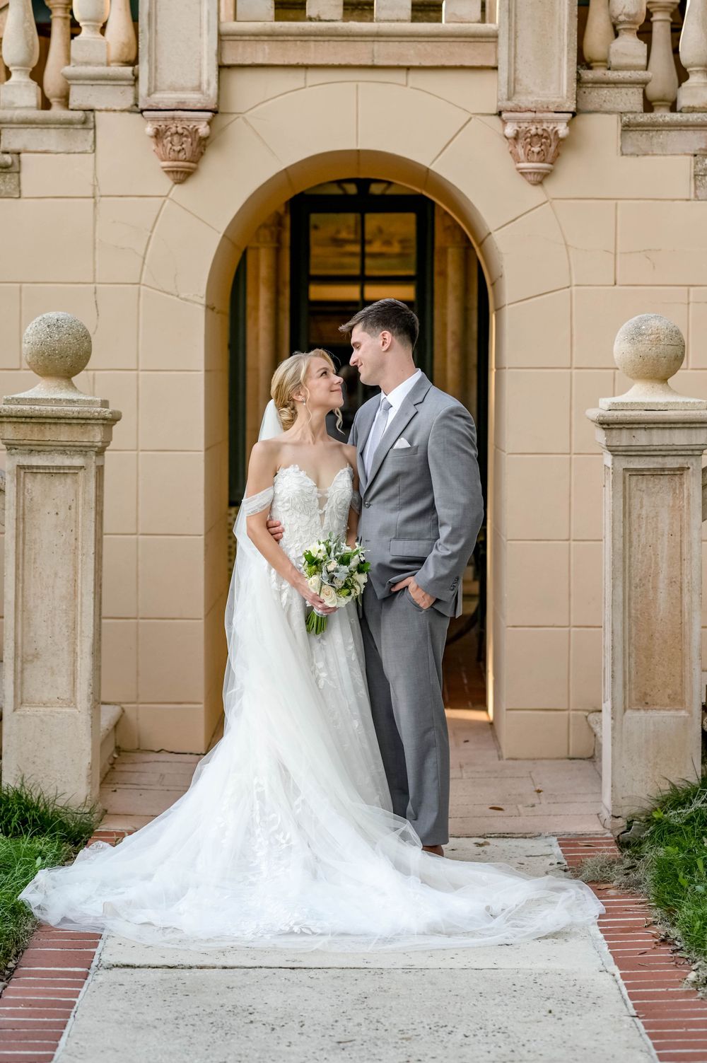 Elegant wedding portrait framed by Mediterranean archway and stone columns.