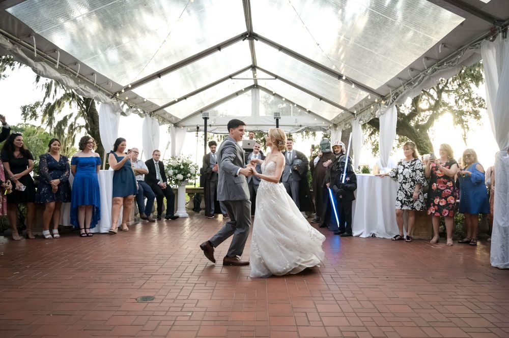 First dance under clear tent with guests watching from the perimeter.