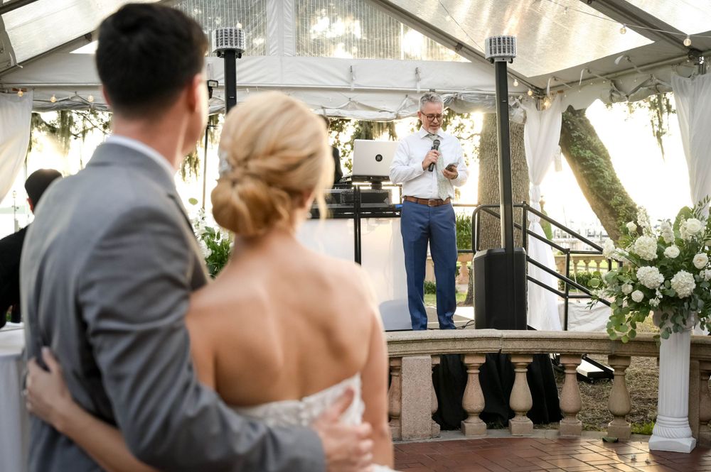 Reception celebration in clear-top tent with speaker giving toast.