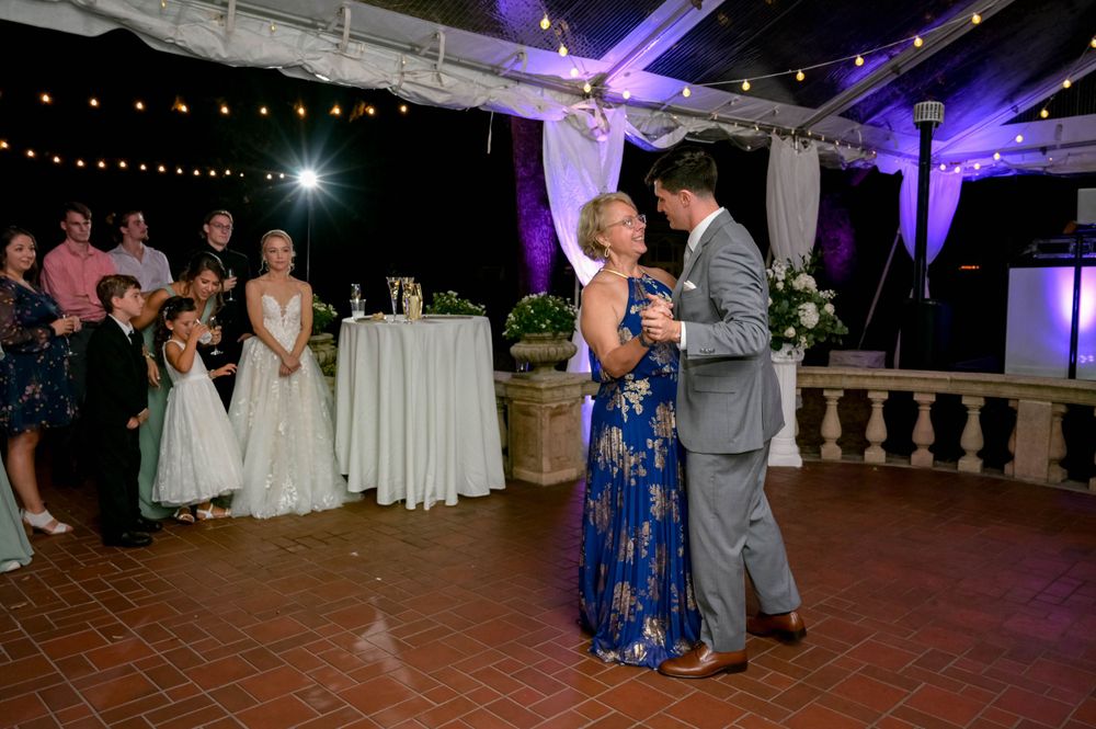 A couple shares a dance at their wedding reception while guests look on.